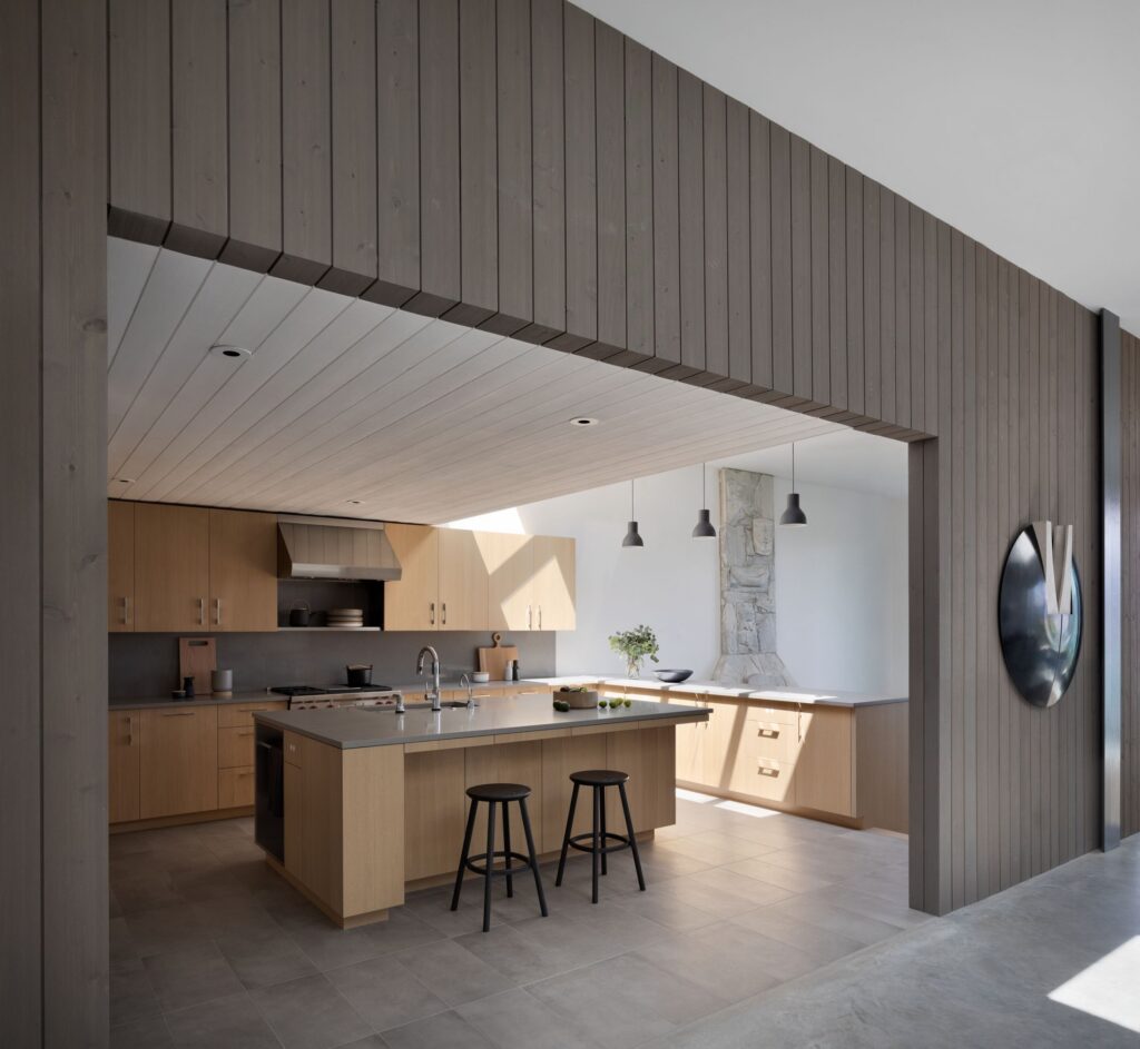 Grey vertical wood walls and ceiling framing a kitchen
